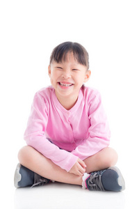快乐的亚洲小女孩坐在白色的脸上微笑。