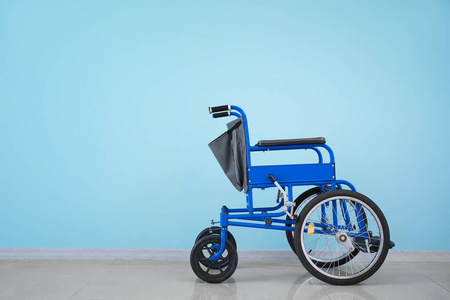 Empty wheelchair near color wall