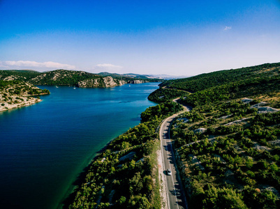 Aerial View of road near blue sea and green mountain in summer C