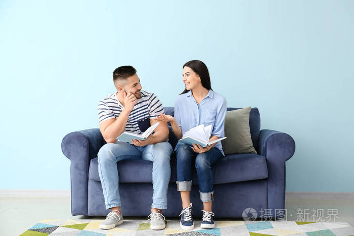 年轻夫妇坐在家里的沙发上看书