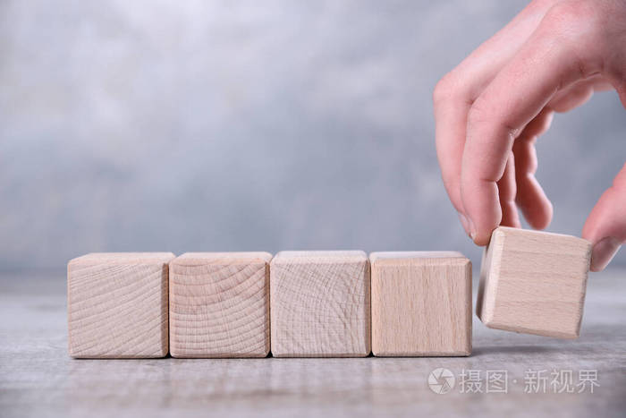 手把空白的木头立方体放在桌子上上面有你的单词字母符号的空间放置
