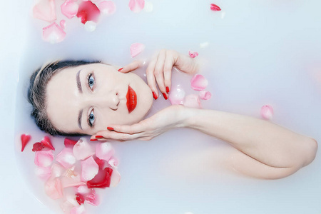 年轻性感的女孩正在用玫瑰花瓣洗澡