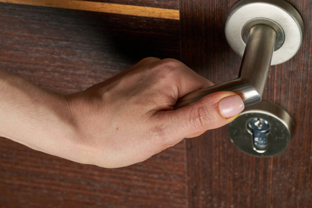 女人用手打开门把手或开门.照片