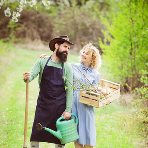 一个农民和他的妻子站在他们的田地里。法玛斯夫妇享受春天的自然，爱护她的植物。地球概念。