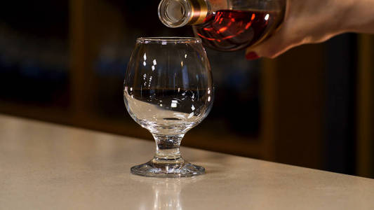 库存镜头.在一间昏暗的房间背景上,用手往玻璃杯里倒酒.照片