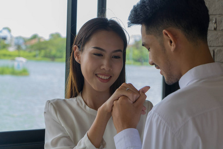 亚洲年轻人拿着结婚戒指盒在咖啡里结婚
