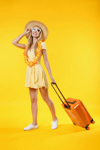 黄底隔离行李箱，头戴礼帽的旅游妇女的垂直镜头