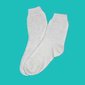 温暖的白色针织袜子，隔离在绿松石背景上。设计对象，项目。温馨舒适健康的理念。
