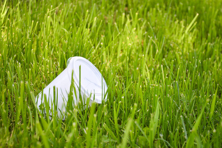 草地上的塑料杯。环境污染的概念，拒绝塑料制品，使用天然材料包装。