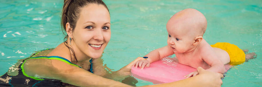 美丽的妈妈在游泳池里教可爱的小女孩游泳。孩子在水里玩得开心妈妈横幅，长格式