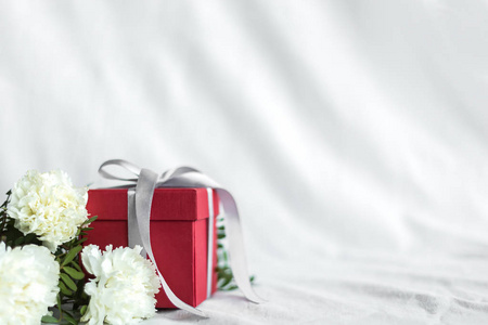 白色织物背景上，鲜花和礼品盒生日快乐，母亲节和情人节快乐。礼品卡。选择性聚焦。复制空间