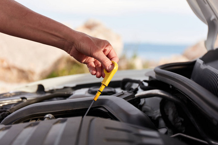 Checking engine oil. A womans hand holding an oil bayonet in a 