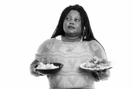 体贴的非洲黑人胖女人拿着一碗放在白色盘子里的薯片和生菜