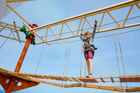 快乐的小男孩在高绳道上攀爬.积极的孩子在家庭度假时进行冒险和行动.