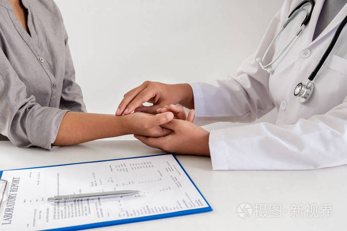 女医生与病人握手，用手指检查上臂脉搏，在医院进行初步健康检查。治疗和健康概念