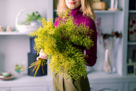  young florist girl with a big bouquet of mimosa in hands