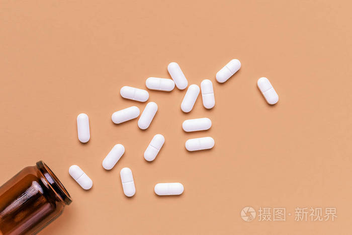 涂膜白色椭圆形药丸从瓶子里溢出俯视图