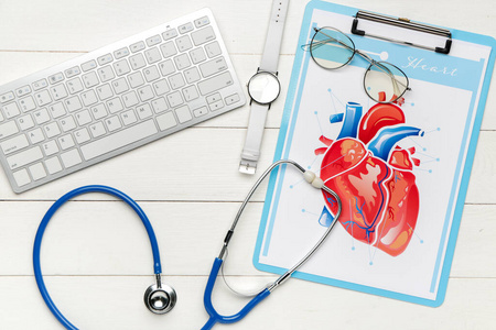 电脑键盘听诊器和木桌上的人体心脏图