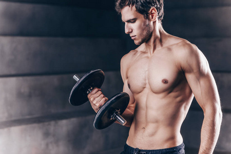 Handsome young muscular man exercising with dumbbells. 