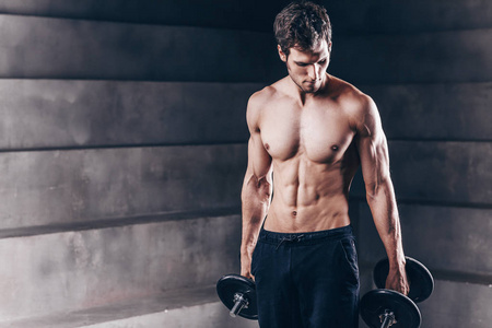 Strong muscle man posing with dumbbell. 