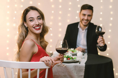 千禧一代情侣在餐厅共进浪漫晚餐，对着镜头摆姿势