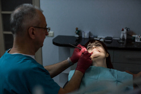 年轻的女性病人和正在接受牙科治疗的资深男性牙医。