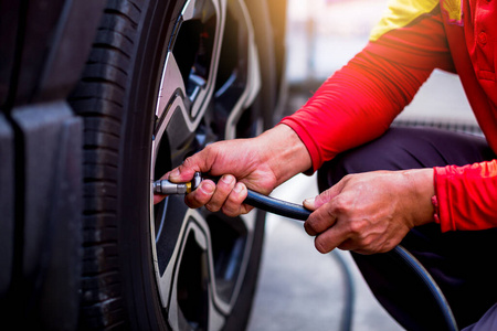 Driver checking air pressure and filling air in the tires close 