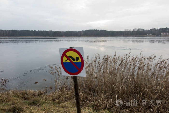 no bathing or swimming sign set on the shore of a lake covered