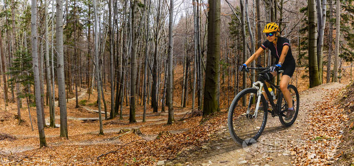 mountainbikingwomanridingonbikeinsummermountainsforest