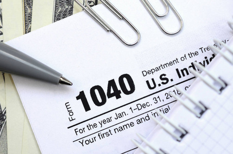 The pen, notebook and dollar bills is lies on the tax form 1040 
