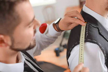 男裁缝在工作室为顾客量尺寸照片