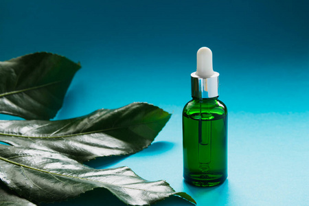 精华液瓶子一个装有化妆品天然精华液,油或植物提取物的瓶子立在一棵