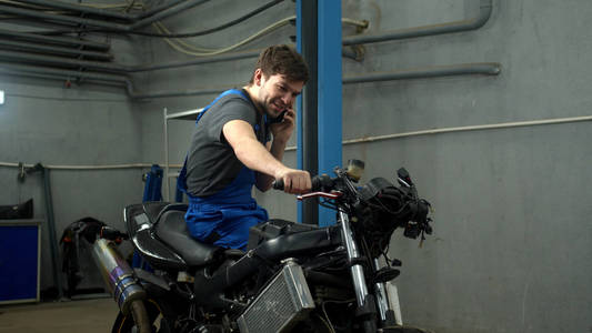 慢动作，技师坐在摩托车上打电话