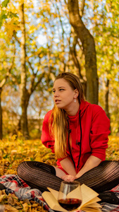 一个穿着红裙子的漂亮女孩。背景是美妙的秋天。艺术摄影。