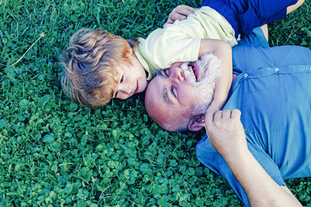 Embrace on green grass  grandfather and grandson. Grandfather w