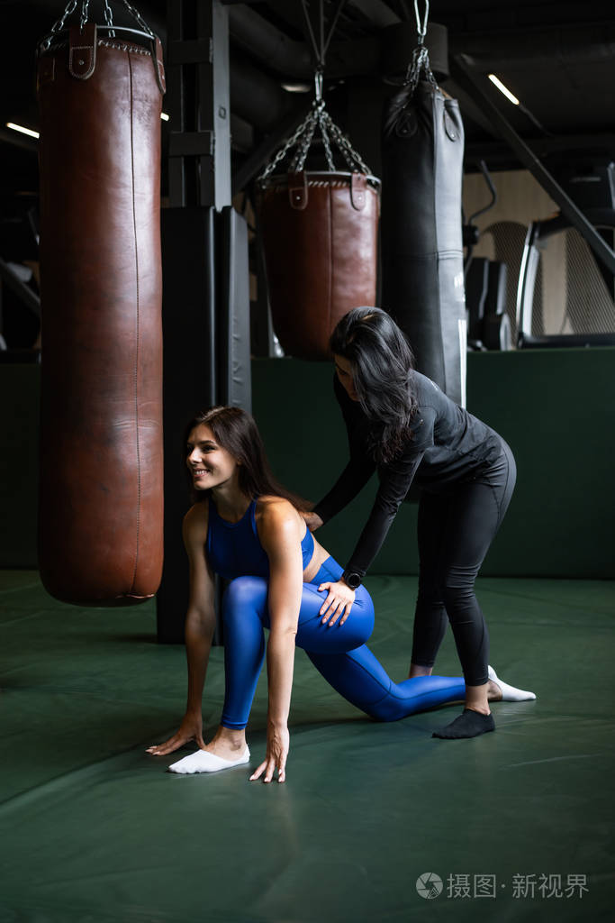 两个漂亮的年轻女孩在健身房健身伸展背部和腿部的肌肉