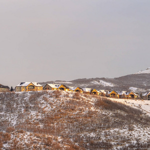 在夕阳下，白雪皑皑的小山顶上，方格结构的邻居们顶着多云的天空