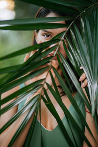 年轻女士用奇异的绿色植物遮脸图片
