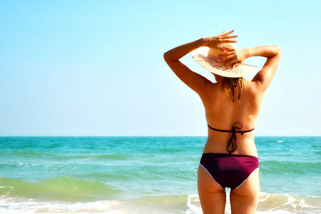 海滩上戴帽子的女人。在海里穿泳衣的女孩。热带暑假