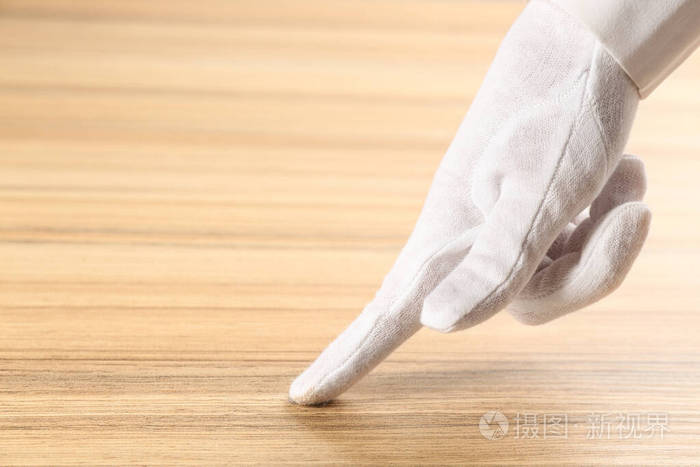 戴白手套的人检查木桌的清洁度