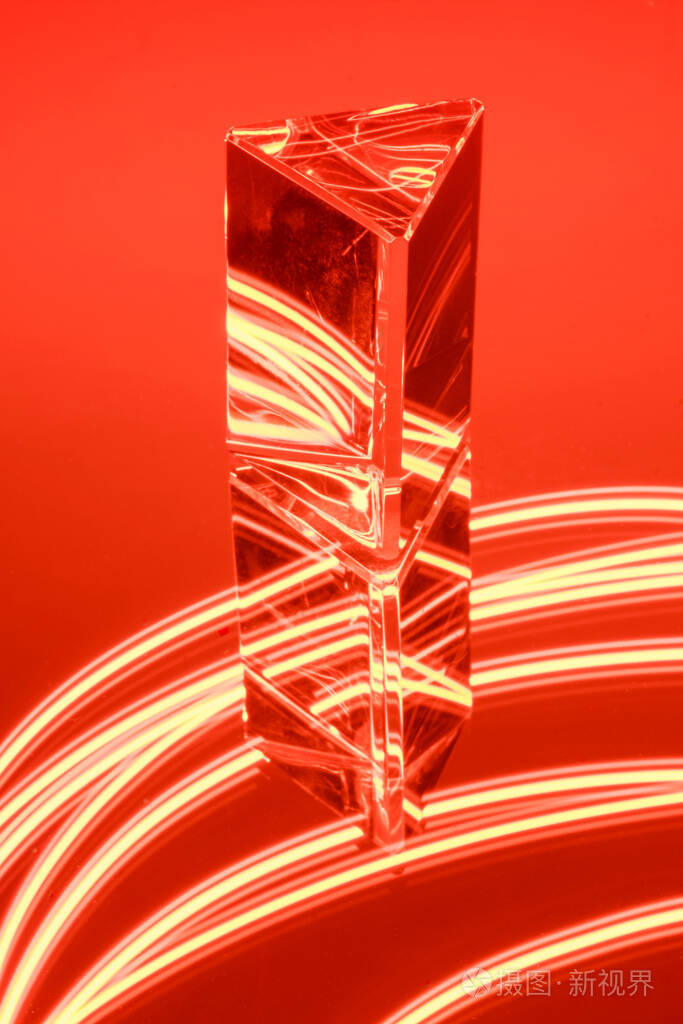 在抽象的红色霓虹灯背景上反射的玻璃棱镜
