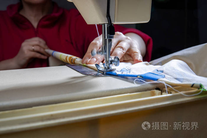 女裁缝手拿纺织品缝制衣服.缝纫过程的模糊背景特写镜头.