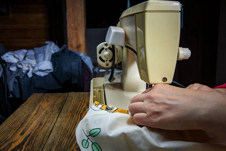 女裁缝手拿纺织品缝制衣服.缝纫过程的模糊背景特写镜头.照片