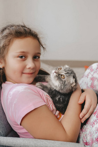 漂亮的小女孩和一只漂亮的苏格兰折叠小猫。侧视图