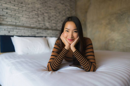 年轻的亚洲女人快乐的微笑在卧室的床上放松