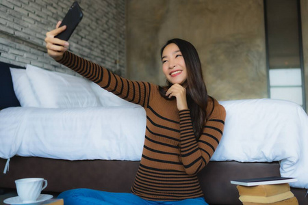 年轻的亚洲女性用智能手机阅读书籍和合作