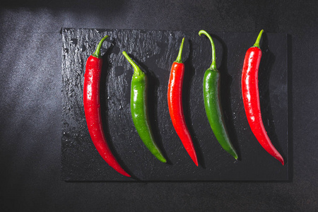 Red and green chillies on blackboard base on black background. T