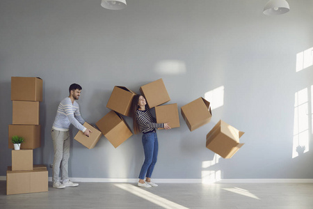 快乐有趣的夫妇拿着纸板箱搬进新公寓房间