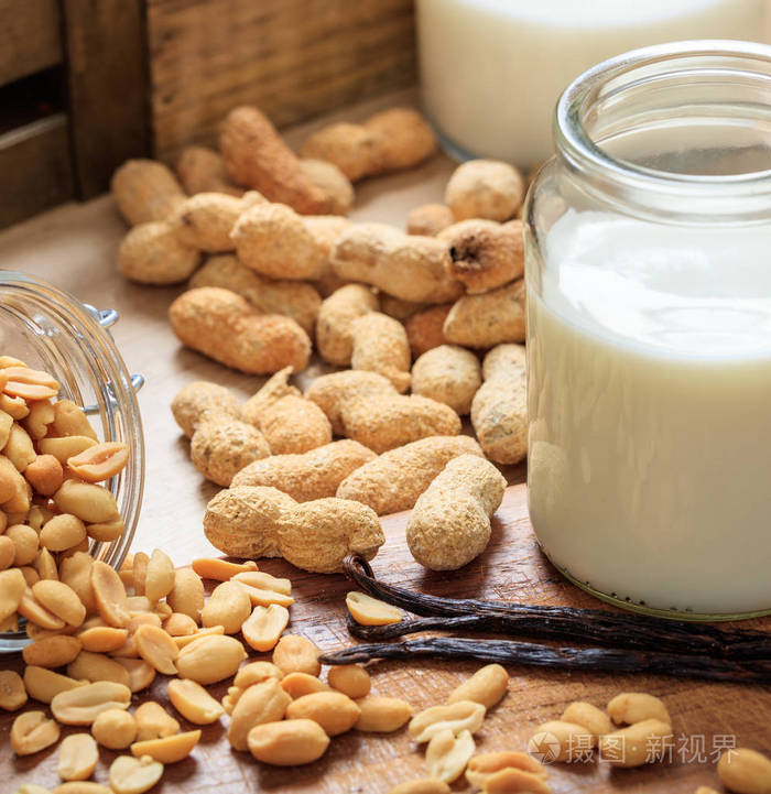 木桌子上的花生奶坚果和牛奶杯素食者和素食者的非乳制品牛奶