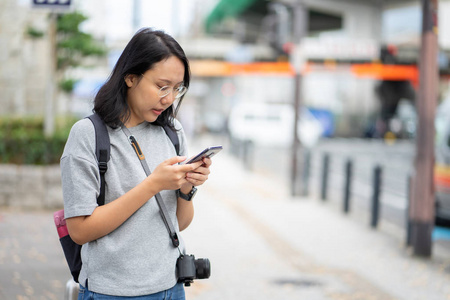 美丽的亚洲女旅行者在市中心使用智能手机